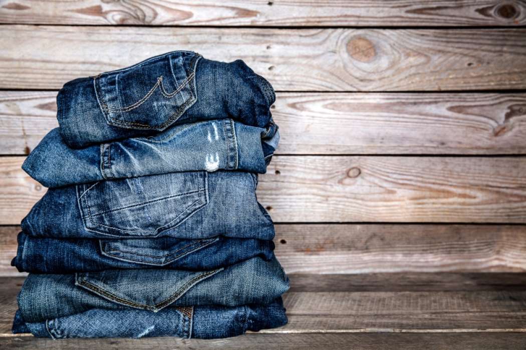 fashionable-clothes.-pile-of-jeans-on-a-wooden-background