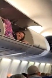 V letalu si je postlala v predalu nad glavami