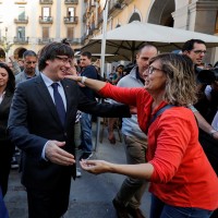 Sacked Catalan President Carles Puigdemont greets a supporter after leaving a restaurant the day