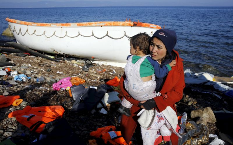 An Afghan migrant carries her baby after arriving by a raft on the Greek ber 19, 2015