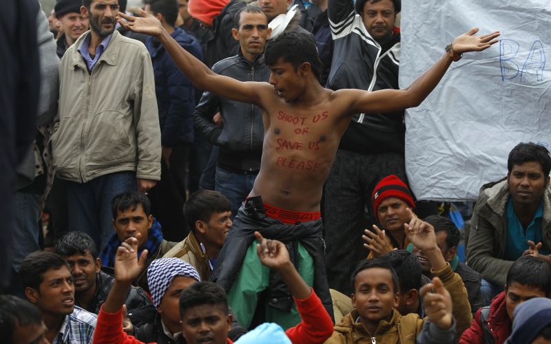 Migrants react, as they wait to cross the border from Greece to Gevgelija
