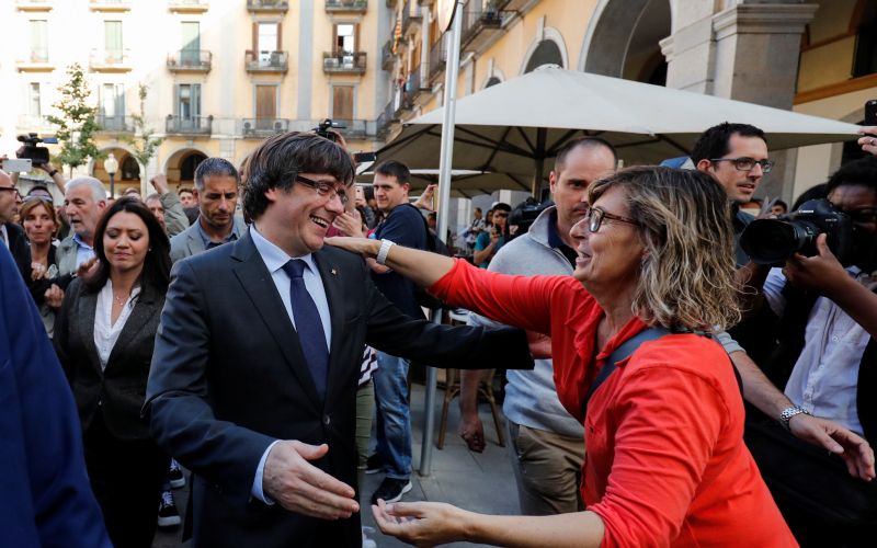 Sacked Catalan President Carles Puigdemont greets a supporter after leaving a restaurant the day