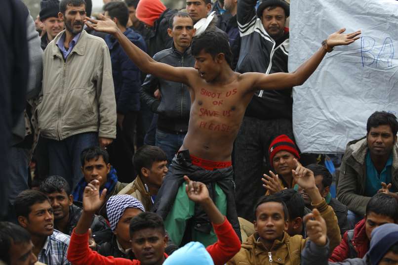 Migrants react, as they wait to cross the border from Greece to Gevgelija