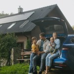 Družina pred hišo, solarni paneli, sončna elektrarna, električni avto