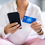 ženska s telefonom in kreditno kartico