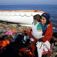 An Afghan migrant carries her baby after arriving by a raft on the Greek ber 19, 2015