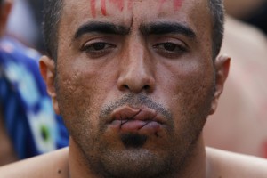 Na meji ujeti migranti so si protestno zašili usta