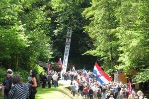 Spominska maša pri Hudi jami, nad Barbara rovom pa napis »Tito morilec«