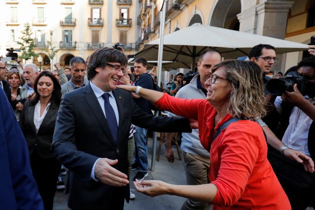 Sacked Catalan President Carles Puigdemont greets a supporter after leaving a restaurant the day