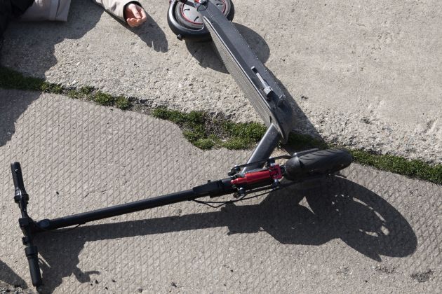 full-shot-man-electric-scooter-laying-ground.jpg