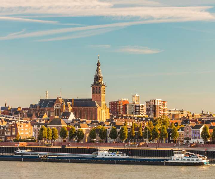 Nizozemsko mesto Nijmegen med sončnim zahodom in z reko Waal, kjer se je začela kolesarska avantura.
