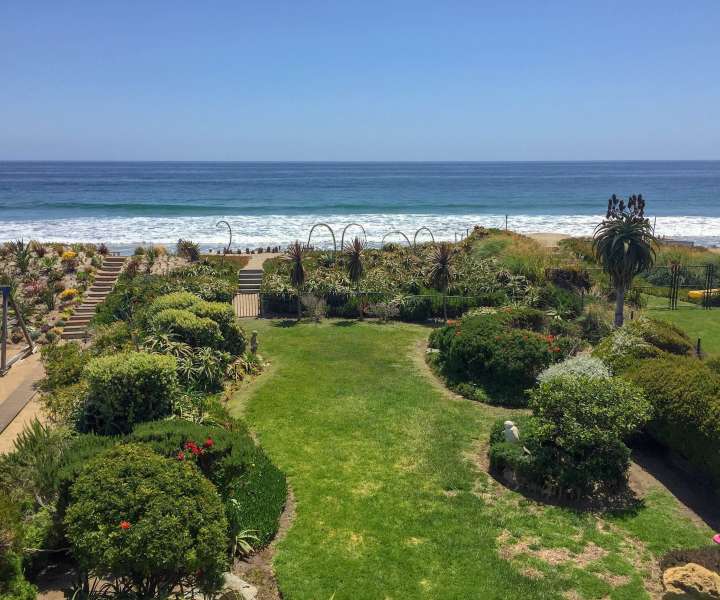 Prostoren vrt, poln okrasnih grmovnic, vodi do zasebne peščene plaže.