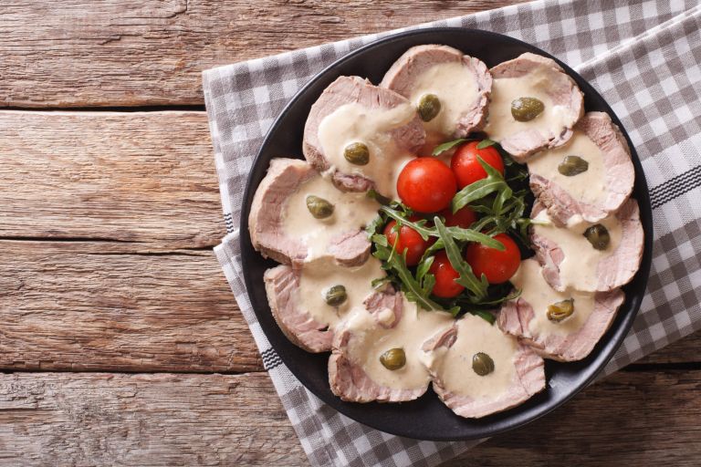 Italian cuisine: Vitello tonnato with capers, arugula, tomatoes close-up. Horizontal top view