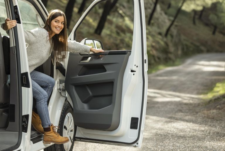 side-view-smiley-woman-getting-out-car-while-road-trip.jpg