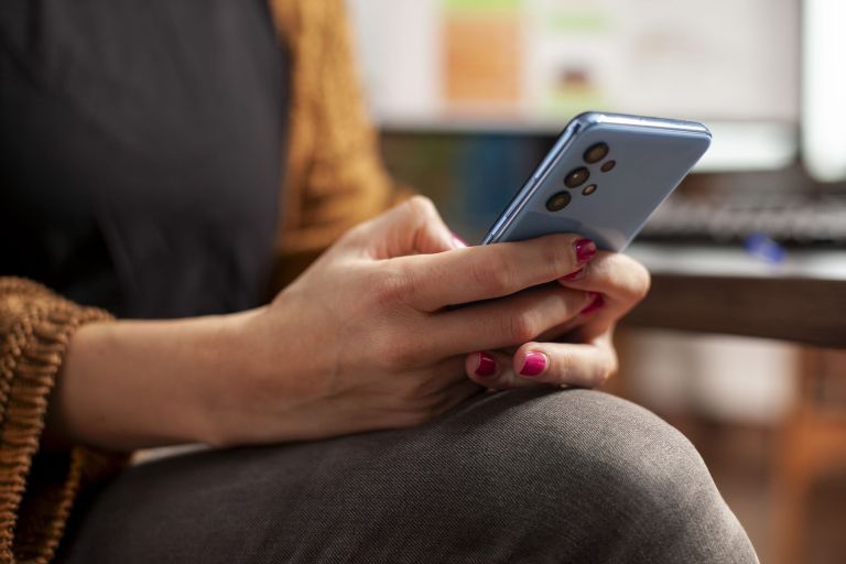 ženska s pametnim telefonom v roki