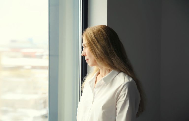 ženska gleda skozi okno