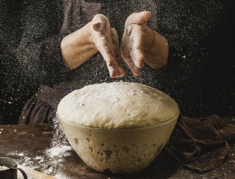 front-view-female-chef-dusting-her-hands-with-flour-before-handling-pizza-dough.jpg