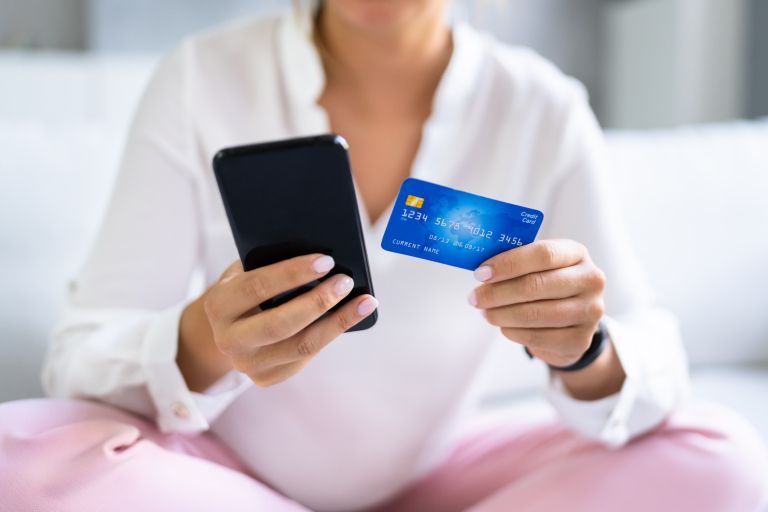 ženska s telefonom in kreditno kartico