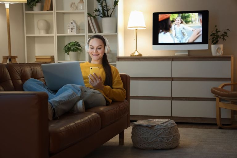 ženska uporablja televizijo, prenosnik in mobilni telefon