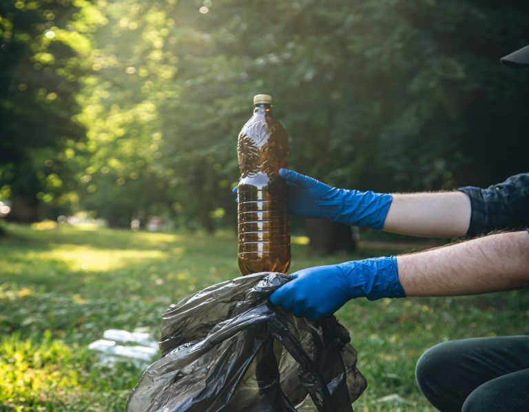closeup-plastic-bottle-male-hand-cleaning-up-nature.jpg