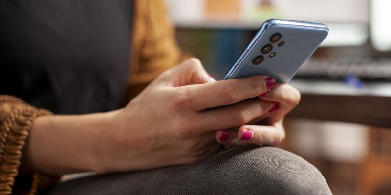 ženska s pametnim telefonom v roki