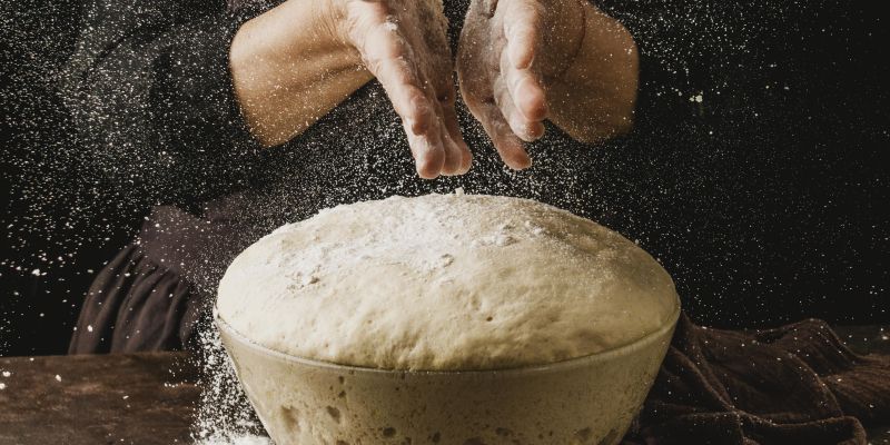 front-view-female-chef-dusting-her-hands-with-flour-before-handling-pizza-dough.jpg