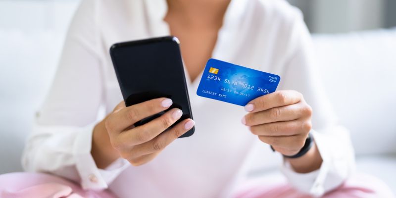 ženska s telefonom in kreditno kartico