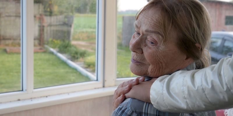 starejša ženska gleda skozi okno