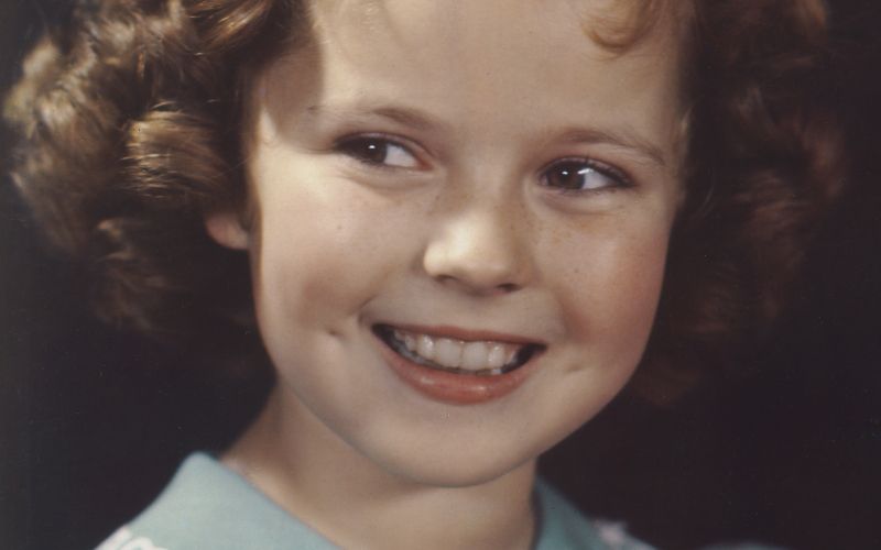 Shirley Temple kot desetletnica s pegicami, pentljo in kodrčki