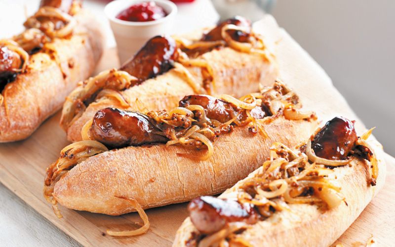 Hotdog s pečenico in gorčično čebulo