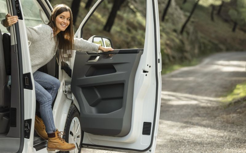 side-view-smiley-woman-getting-out-car-while-road-trip.jpg