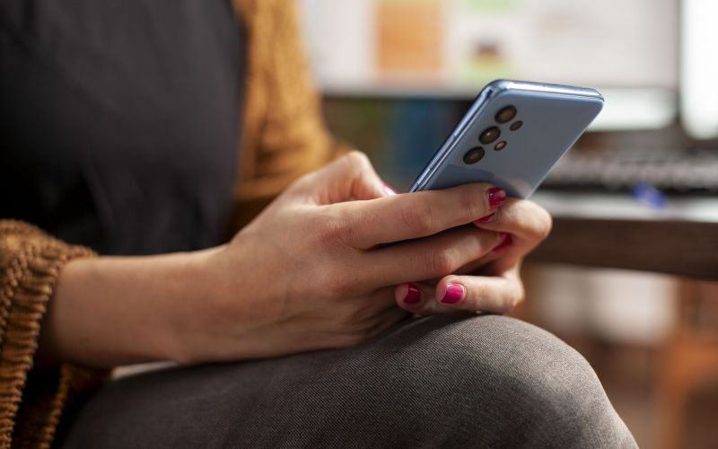 ženska s pametnim telefonom v roki