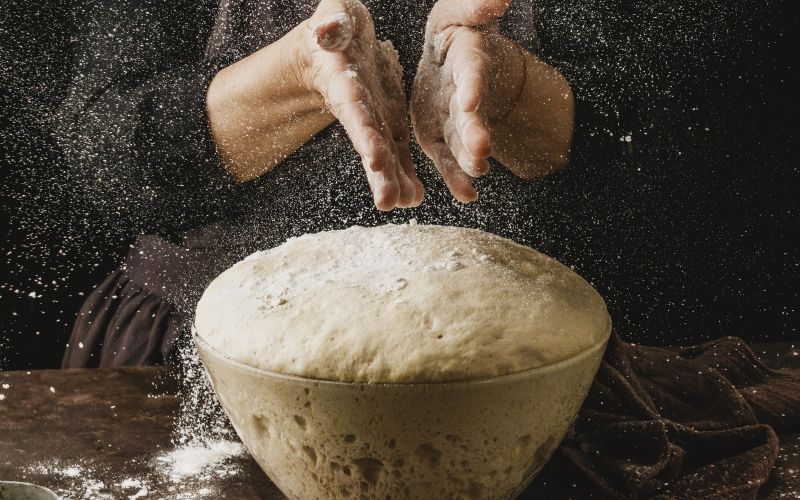 front-view-female-chef-dusting-her-hands-with-flour-before-handling-pizza-dough.jpg