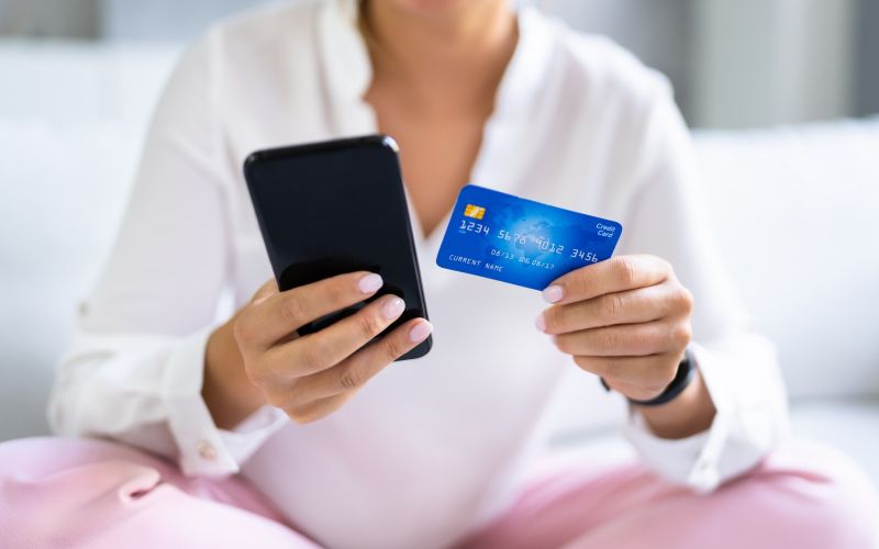 ženska s telefonom in kreditno kartico