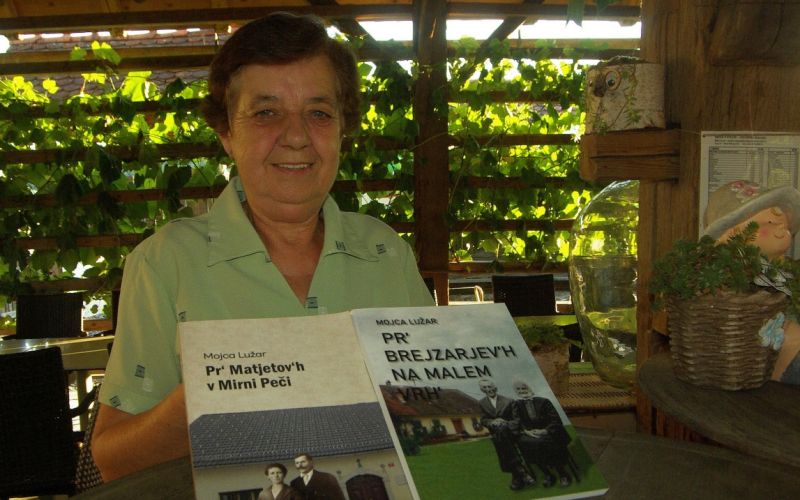 Mojca Lužar z obema knjigama, v katerih je popisala mamin in očetov rod